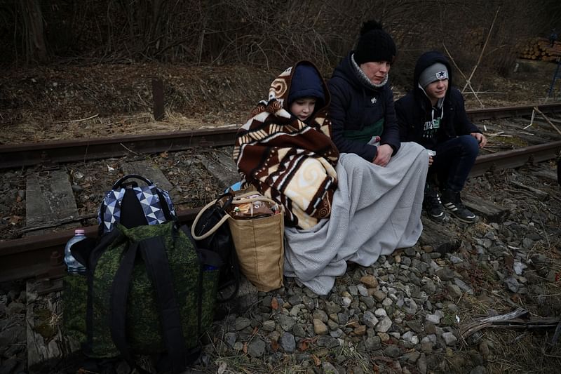 People sit on the railway after crossing the border between Poland and Ukraine, after Russia launched a massive military operation against Ukraine, in Kroscienko, Poland on 27 February, 2022