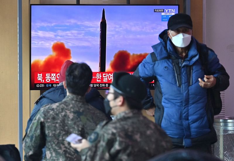 People watch a television screen showing a news broadcast with file footage of a North Korean missile test, at a railway station in Seoul on 27 February, 2022, after North Korea fired an "unidentified projectile" according to the South's military