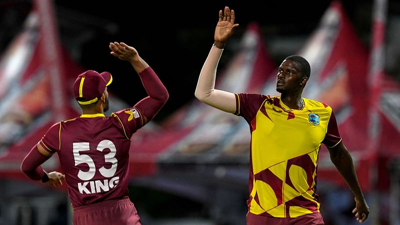 Jason Holder (R) of West Indies celebrates the dismissal of Chris Jordan of England during the 5th and final T20I between West Indies and England at Kensington Oval, Bridgetown, Barbados, on 30 January, 2022