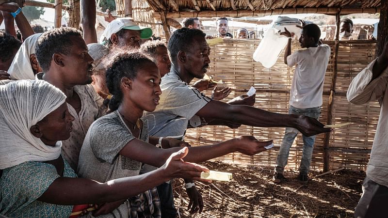 Ethiopian refugees who fled the Tigray conflict ask for plastic sheets at the Um Raquba refugee camp in Sudan's eastern Gedaref state, on 5 December, 2020