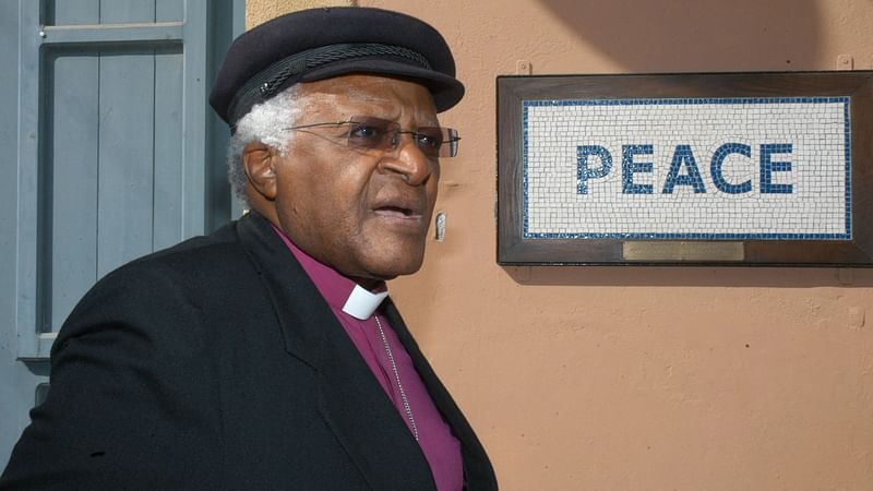 In this file photo taken on 9 October 2008 South African cleric and anti-apartheid campaigner Desmond Tutu walks past a street mosaic which reads 'Peace' on the green line that separates the Greek Cypriot side from the Turkish military-controlled areas in the heart of Nicosia