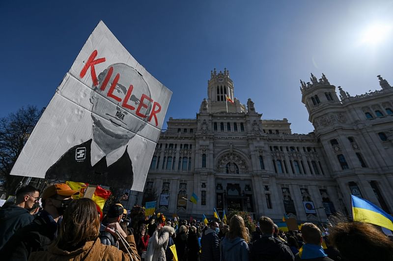 A demonstrator holds a sign depicting Russian President Vladimir Putin and reading "Killer" in front of the Cibeles Palace during a protest against Russia's invasion of Ukraine on the Plaza de Cibeles square in Madrid on 27 February 2022.