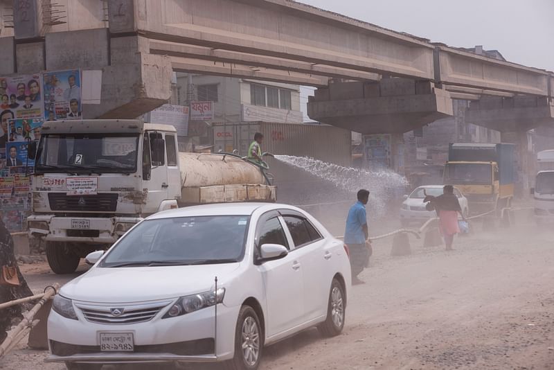 A man sprays water on the road in order to reduce dust as air pollution worsens during winter in Tongi area of Gazipur, Bangladesh, on 3 February 2022