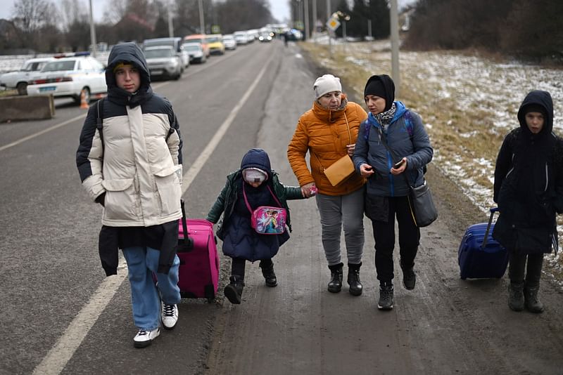 An Ukrainian family walks towards the Medyka-Shehyni border crossing between Ukraine and Poland as they flee the conflict in their country, near the Ukrainian village of Tvirzha, some 20km from the border, on 28 February, 2022