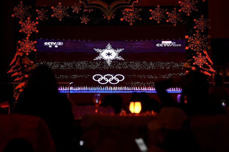 People watch a screen with live footage of the closing ceremony of Beijing 2022 Winter Olympics Games, at a bar in Beijing on 20 February