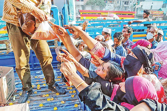 With prices spiralling in the open market, people wait for fair-price commodities at the TCB trucks in Mohammedpur in the capital city on 12 March 2022