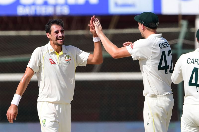 Australia's Mitchell Starc (L) celebrates with teammate Cameron Green (R) after the dismissal of Pakistan's Hasan Ali during the third day of the second Test cricket match between Pakistan and Australia at the National Cricket Stadium in Karachi on 14 March, 2022.