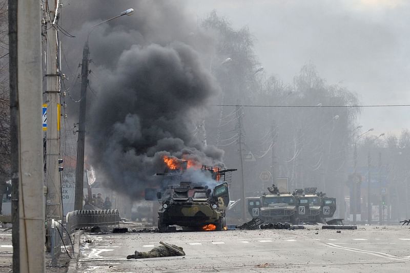 This photograph taken on 27 February , 2022 shows a Russian Armoured personnel carrier (APC) burning next to unidentified soldier's body during fight with the Ukrainian armed forces in Kharkiv