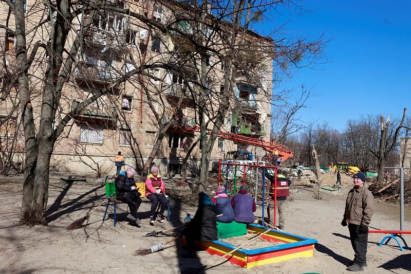 Workers take a rest after cleaning the area near an apartment building destroyed during an air raid, amid Russia's invasion of Ukraine, in Kyiv, Ukraine on 21 March, 2022