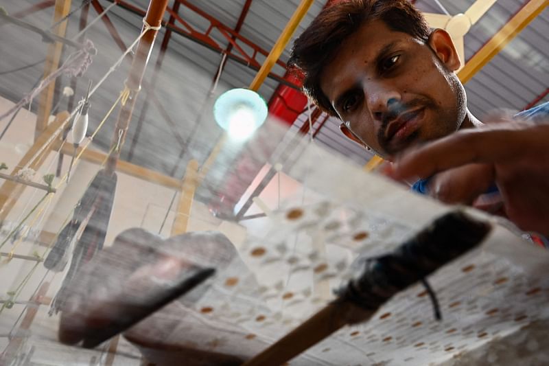 In this picture taken on 8 January, 2022, a weaver uses a handloom to make traditional muslin garments at the Dhakai Muslin Project facility in Narayanganj