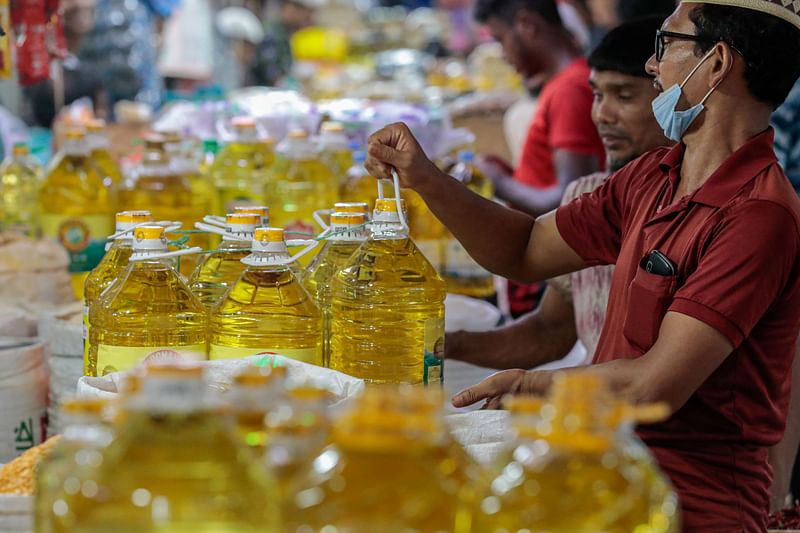 A man holds a bottle of soybean oil at a grocery shop