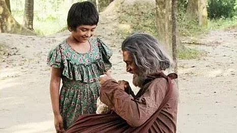 Gazi Rakayet and a child artiste in a scene from 'Gor' (The Grave)