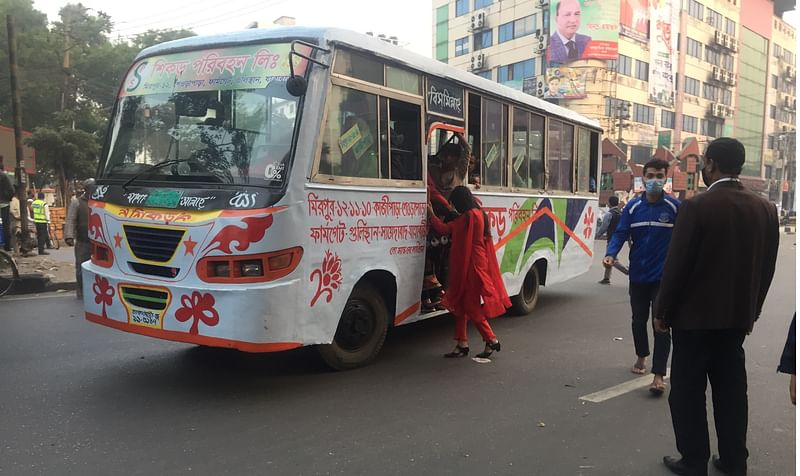 An office-going woman runs to board a running bus at the zero point of Dhaka's Gulistan area