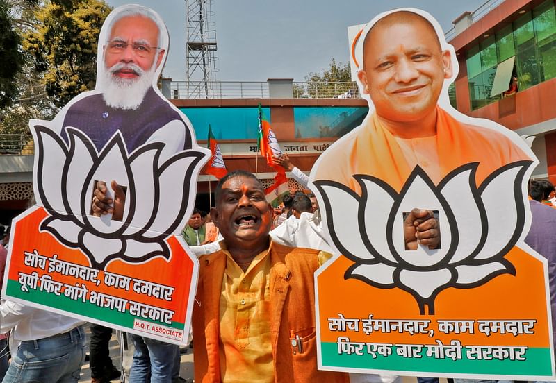 A supporter of India's ruling party Bharatiya Janata Party (BJP) displays cut-outs of prime minister Narendra Modi and Chief Minister of Uttar Pradesh Yogi Adityanath as he celebrates after learning the initial poll results outside its party office in Lucknow, India, 10 March, 2022