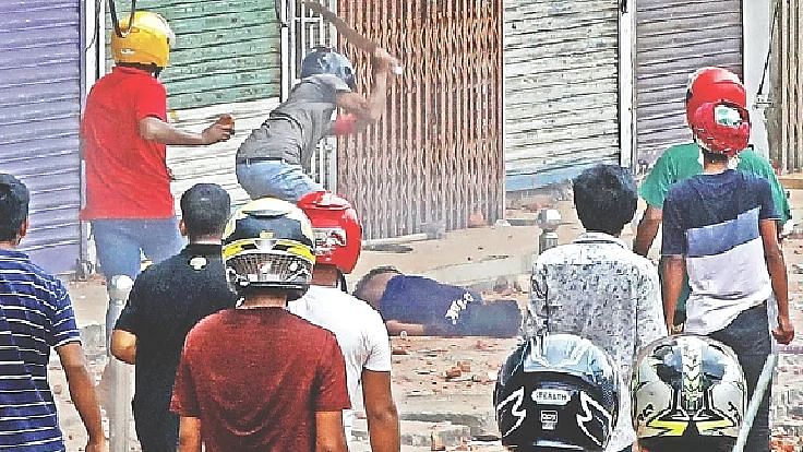 A person, wearing a helmet chops delivery person Nahid Hossain lying on the sideway during the clash between Dhaka College students and New Market shop owners and workers on 19 April 2022