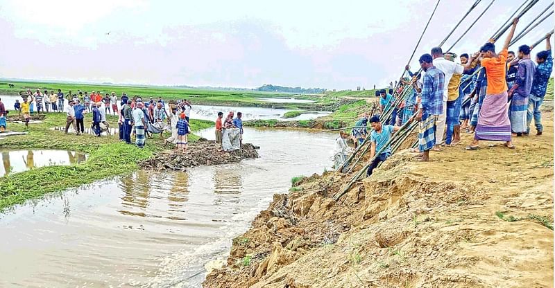 People are trying to protect a dam in Bishwambhar upazila of Sunamganj on Tuesday.