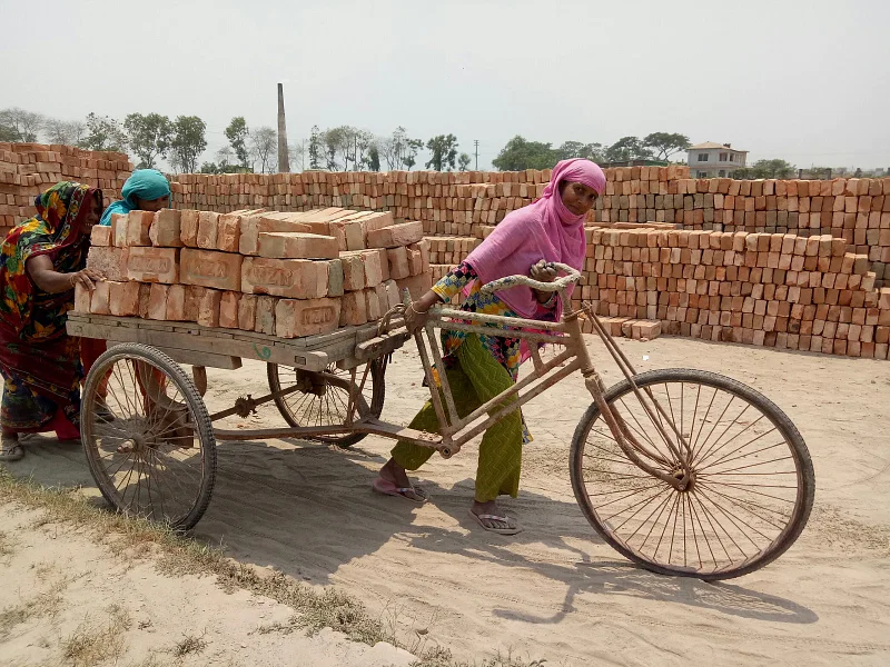 A woman pulls and two other women push a rickshaw van in Amin Bazar area, Savar, Dhaka