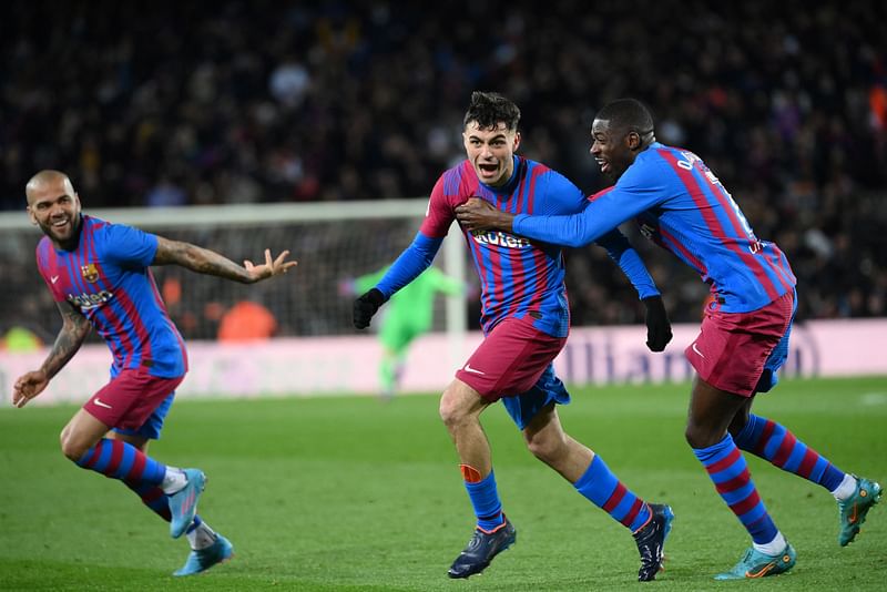 Barcelona's Spanish midfielder Pedri celebrates scoring the opening goal with Barcelona's French forward Ousmane Dembele (R) and Barcelona's Brazilian defender Dani Alves (L) during the Spanish League football match between FC Barcelona and Sevilla FC at the Camp Nou stadium in Barcelona on 3 April, 2022