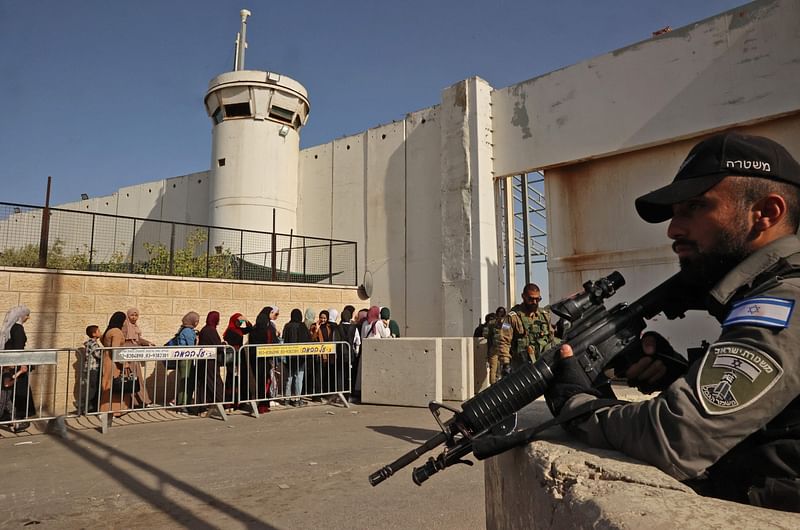 Israeli security forces keep watch as Palestinians cross a checkpoint to reach the city of Jerusalem to attend the last Friday prayers of Ramadan in the al-Aqsa mosque compound, on 29 April, 2022 in Bethlehem in the occupied West Bank.