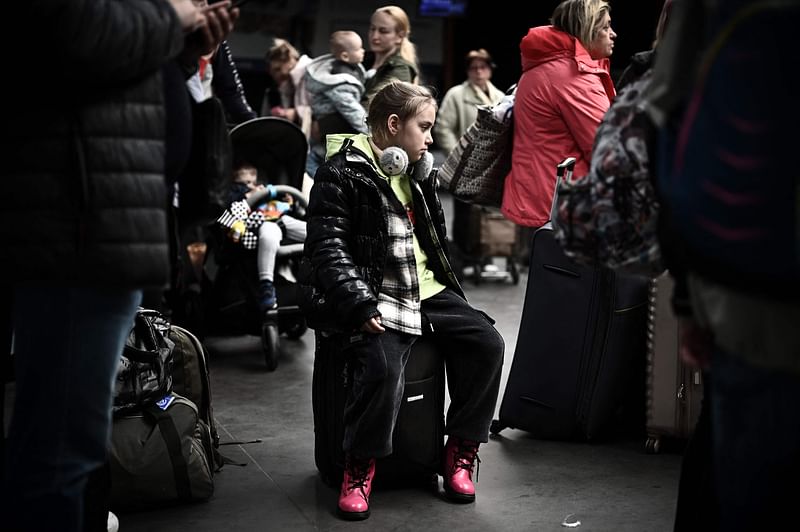 A young Ukrainian refugee sits on a suicatse after disembarking from Moldova at the international airport of Bordeaux in Merignac on 21 April, 2022