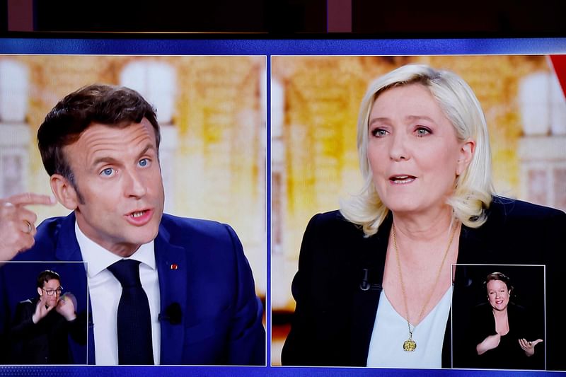 A picture shows a TV screen displaying a live televised between French President and La Republique en Marche (LREM) party candidate for re-election Emmanuel Macron (L) and French far-right party Rassemblement National (RN) presidential candidate Marine Le Pen (R), broadcasted on French TV channels TF1 and France 2, in Saint-Denis, north of Paris, ahead of the second round of France's presidential election.