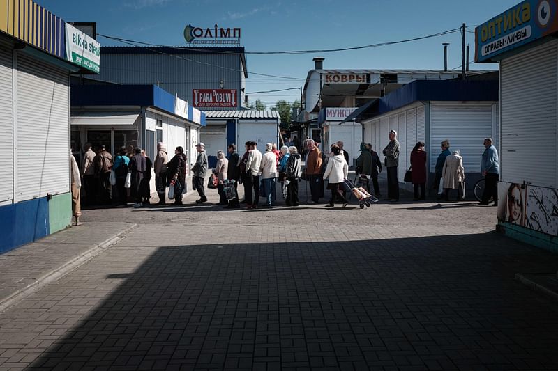 People queue to buy bread in a market, largely empty due to the ongoing conflict, in Kramatorsk, eastern Ukraine, on 29 April 2022, amid Russia's military invasion launched on Ukraine