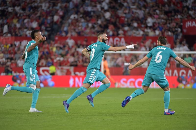 Real Madrid's French forward Karim Benzema (C) celebrates after scoring a goal during the Spanish League football match between Sevilla FC and Real Madrid CF at the Ramon Sanchez Pizjuan stadium in Seville on 17 April, 2022