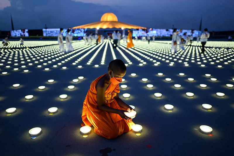 A young Buddhist monk arranges a LED light as part of Earth Day celebrations at the Wat Dhammakaya Buddhist temple in Pathum Thani province, north of Bangkok on 23 April, 2022