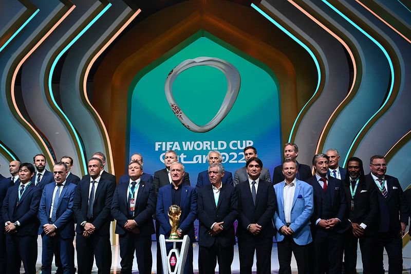 Coaches pose in front of the World Cup trophy during the draw for the 2022 World Cup in Qatar at the Doha Exhibition and Convention Center on 1 April, 2022