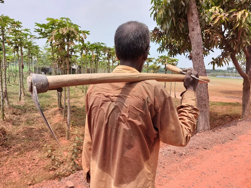 A farmer with a spade returns home as he could not continue working in field due to extreme temperature