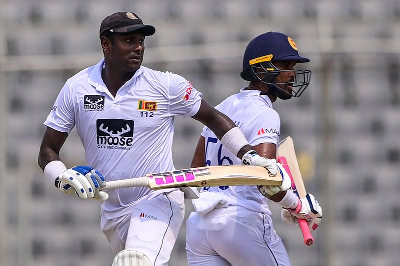 Sri Lanka's Angelo Mathews (L) and Dinesh Chandimal take a run during the fourth day of the second Test cricket match between Bangladesh and Sri Lanka at the Sher-e-Bangla National Cricket Stadium in Dhaka on 26 May, 2022