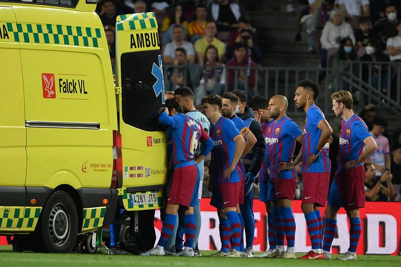 Barcelona's players stand near the ambulance during the evacuation of Uruguayan defender Ronald Araujo after an injury, during the Spanish league football match between FC Barcelona and RC Celta de Vigo at the Camp Nou stadium in Barcelona on 10 May, 2022.