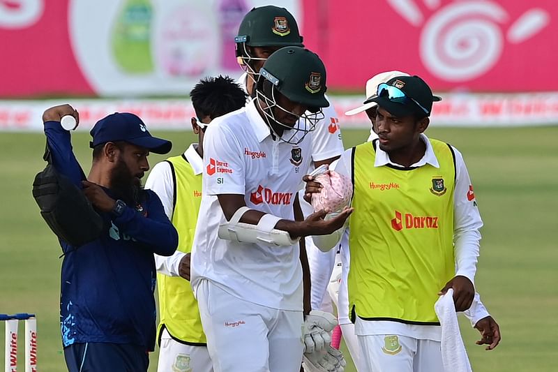 Bangladesh's Shoriful Islam (C) walks back to the pavilion after being injured during the fourth day of the first Test cricket match between Bangladesh and Sri Lanka at the Zahur Ahmed Chowdhury Stadium in Chittagong on 18 May 2022