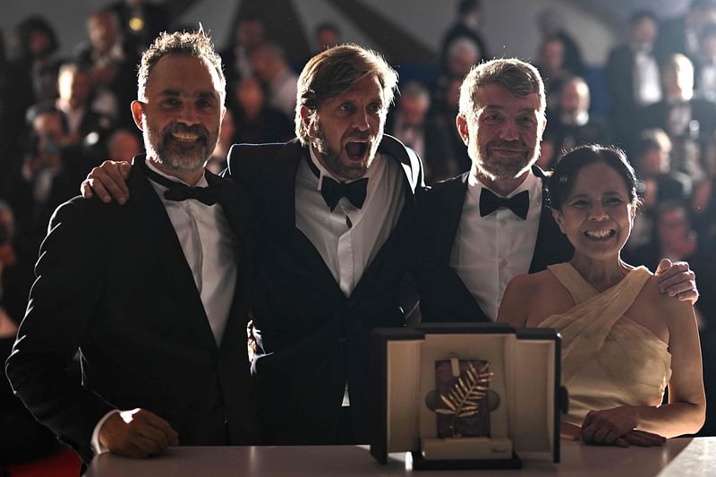 Swedish film director Ruben Ostlund (2L) poses with (from L) Swedish film producer Erik Hemmendorff, film producer Philippe Bober and Filipino actress Dolly de Leon during a photocall after he won the Palme d'Or for the film "Triangle of Sadness" during the closing ceremony of the 75th edition of the Cannes Film Festival in Cannes, southern France, on 28 May, 2022