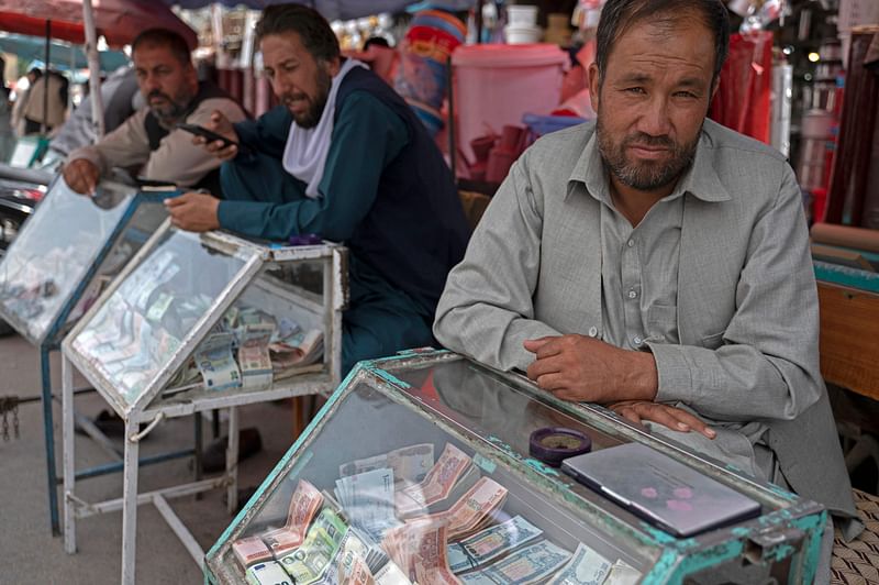 Afghan money changers wait for customers along a street near the currency exchange Sarai Shahzada market in Kabul on 15 May, 2022