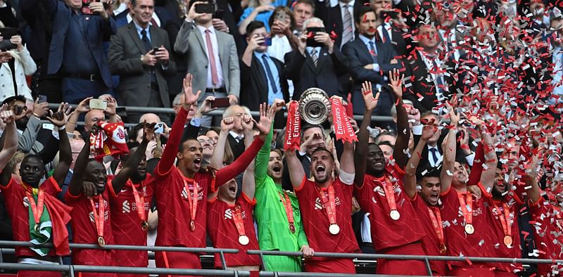 Liverpool's English midfielder Jordan Henderson (C) holds the trophy as he celebrates with teammates after winning the English FA Cup final football match between Chelsea and Liverpool, at Wembley stadium, in London, on 14 May, 2022