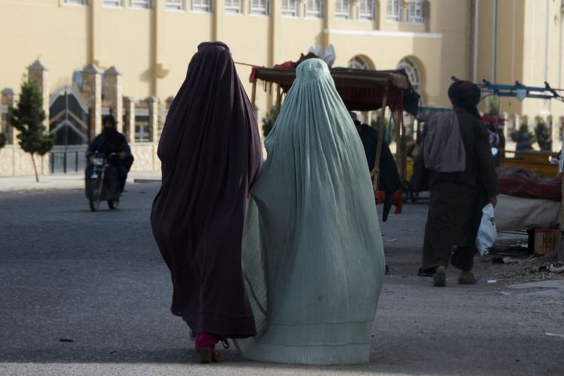 Burqa-clad women walk along a street in Kandahar on 7 May, 2022