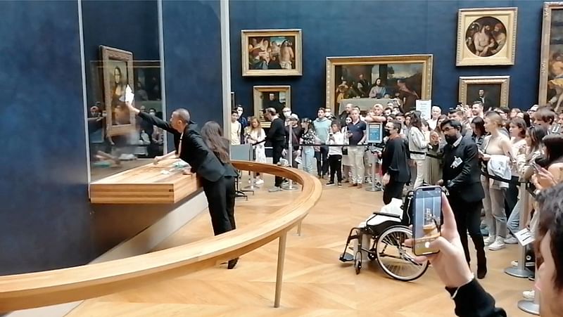 Museum staff clean the protective glass with da Vinci's Mona Lisa behind it, after a visitor smeared it with cream, in Paris, France 29 May, 2022 in this screen grab obtained from a social media video.