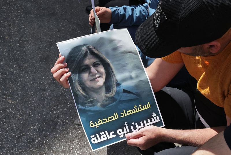 Palestinians hold a poster displaying veteran Al Jazeera journalist Shireen Abu Aqleh, who was, according to the network, shot dead by Israeli troops as she covered a raid on the West Bank's Jenin refugee camp on 11 May 2022, in the West Bank city of Hebron.