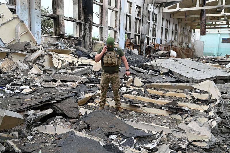 A Ukrainian serviceman talks by phone as he walks through the rubbles of a building of the Polytechnic Sports Complex of the Kharkiv National Technical University after it was hit by Russian missile in Kharkiv on 24 June 2022, amid Russian invasion of Ukraine