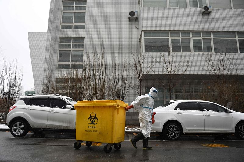 In this file photo taken on 14 February, 2020, a worker carts a bin loaded with medical waste at the Youan Hospital in Beijing