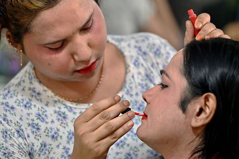 In this picture taken on March 23, 2022, transgender Rohingya beautician Tanya puts makeup on a customer in her beauty parlour near Kutupalong refugee camp in Ukhiya, Cox's Bazar