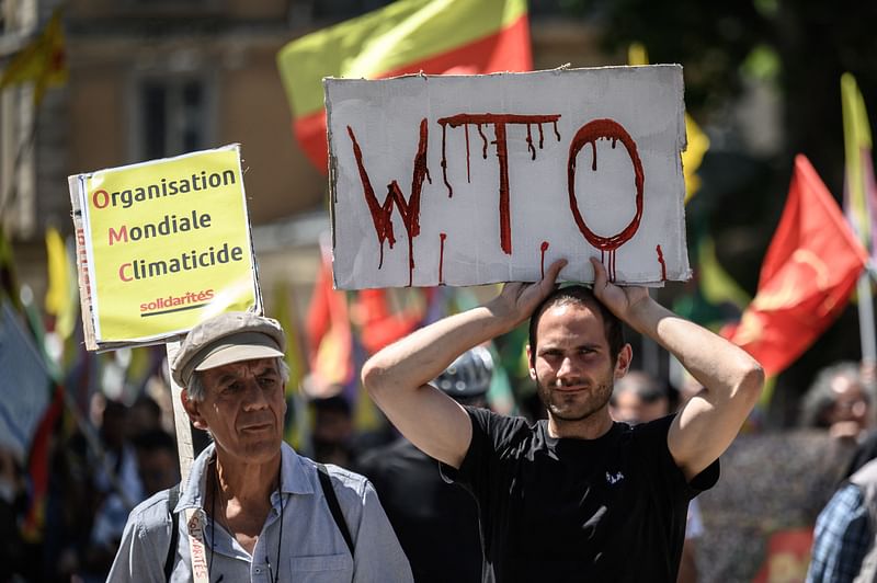 A demonstrator (L) holds a "WTO" placard in a rally against the World Trade Organization on the eve of the WTO Ministerial Conference, in Geneva on 11 June, 2022.