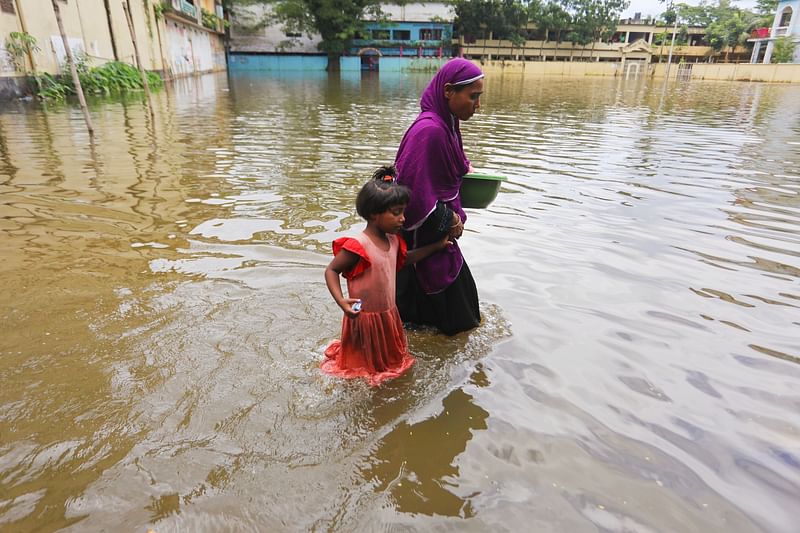 A woman and a child wade across the flooded area. The picture was taken from Osmaninagar in Sylhet on 26 June.