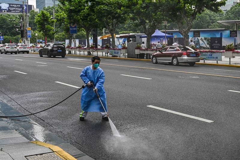 A worker wearing protective gear cleans a street in the Jing'an district of Shanghai on 1 June, 2022, after the end of the lockdown that kept the city two months with heavy-handed restrictions.