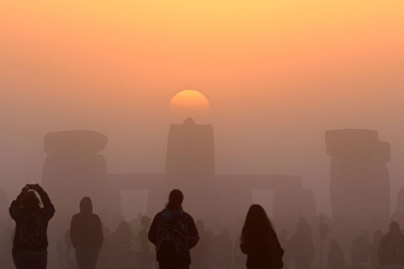 Revellers celebrate the Summer Solstice as the sun rises at Stonehenge, near Amesbury, in Wiltshire, southern England on 21 June, 2022, in a festival, which dates back thousands of years, celebrating the longest day of the year when the sun is at its maximum elevation