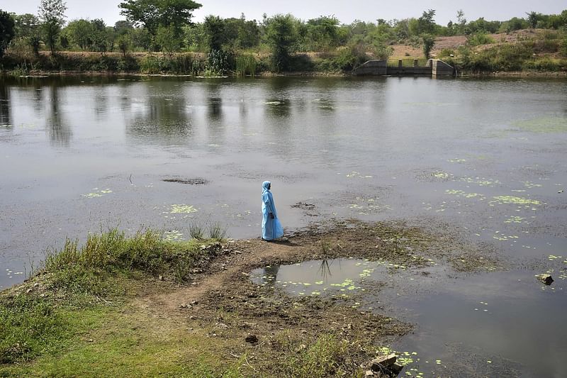 In this picture taken on 10 June, 2022, a member of Jal Saheli ‘Friend of water’ stands near a pond in Agrotha village