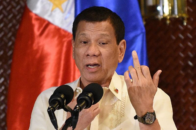 This file photo taken on 18 July, 2017 shows Philippine President Rodrigo Duterte gesturing with his middle finger in an address to military personnel to not give up their weapons so easily while facing the enemy, during a turn-over of some 3,000 .45 calibre handguns to the military at the Malacanang Palace in Manila