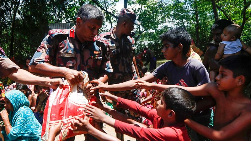 Flood victims receive relief materials distributed by Border guard members in a flooded area following heavy monsoon rainfalls in sunamganj on June 24, 2022.