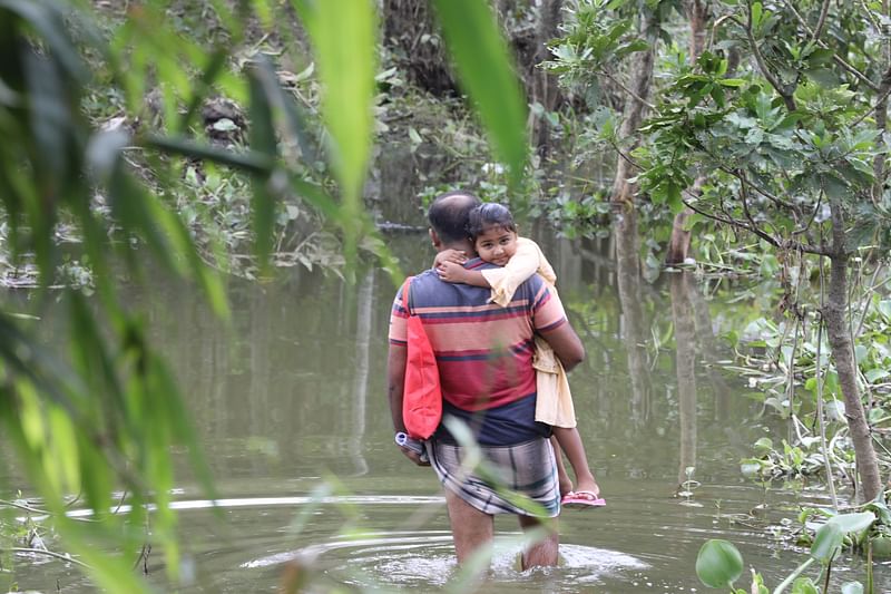 Incessant rain and onrush of upstream water caused massive flooding in Sunamganj. A man wades through knee-deep water carrying his child on the shoulder. The picture was taken from Jonigaon in Sunamganj on 27 June.